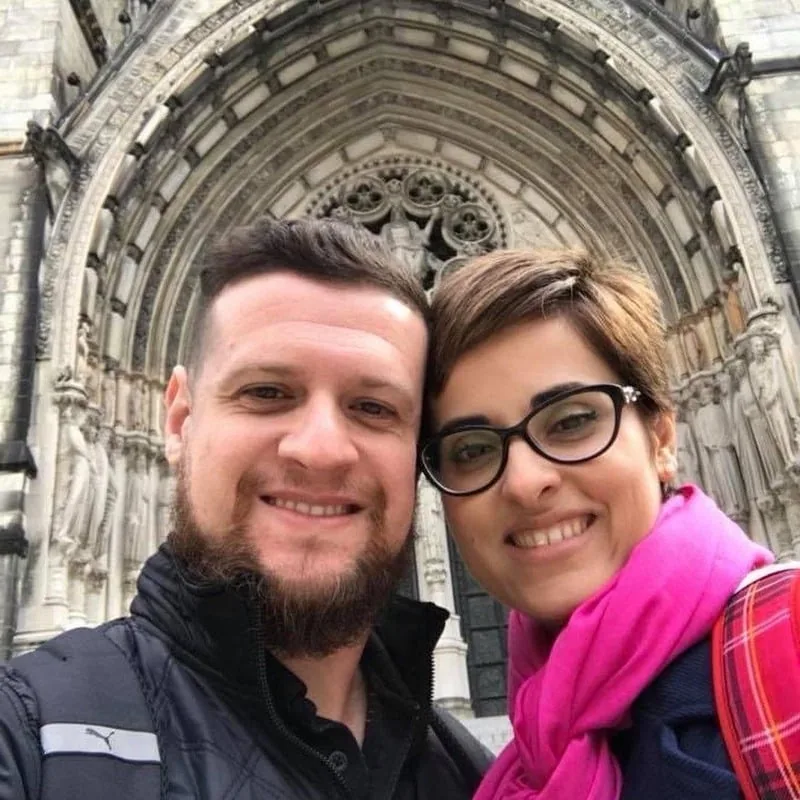 Fabi e Marcelo sorrindo juntos em frente a uma catedral